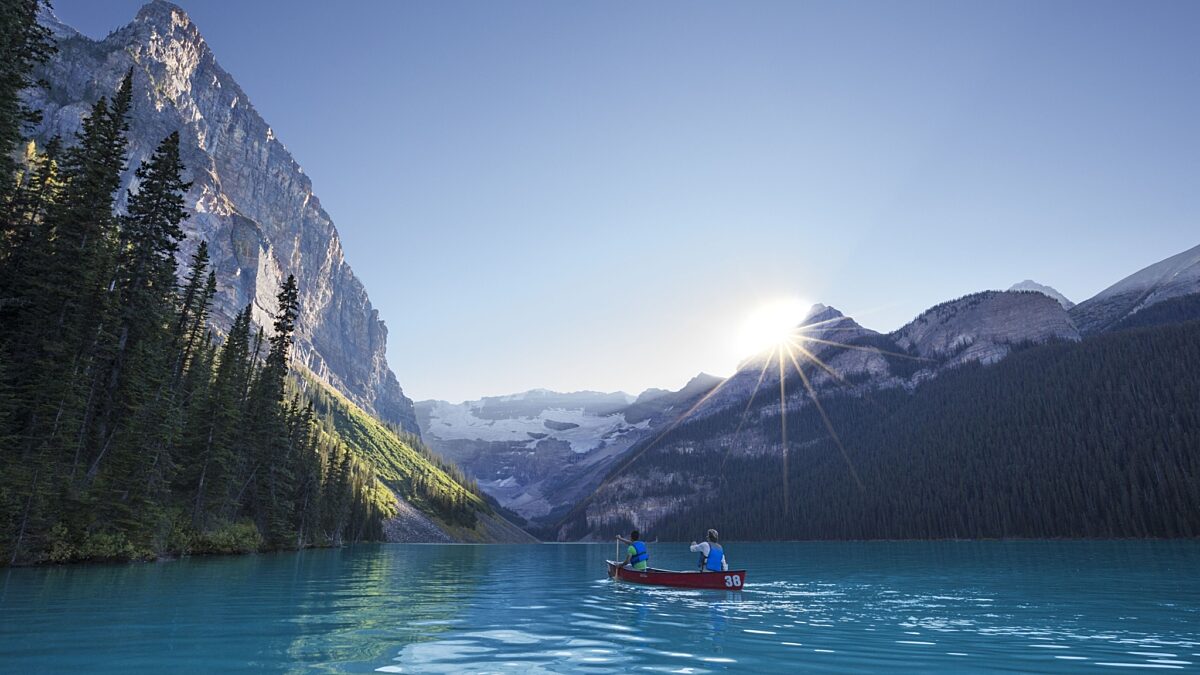 Mountaineer Lodge Lake Louise summer adventure—canoe on turquoise water at sunrise with glacier views and towering Rocky Mountains.